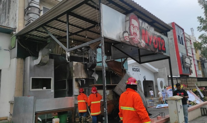 HANGUS: Petugas DPKP melakukan pembasahan depot sate Jalan Niaga Gapura, Lontar, Surabaya. (IST)