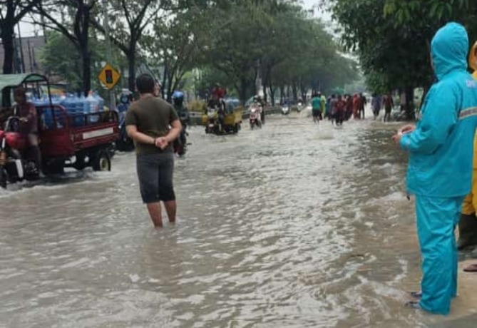 TERGENANG: Hujan dengan intensitas tinggi yang terjadi di Surabaya, Rabu (25/1), menyebabkan Jalan Raya Sememi tergenang. (ISTIMEWA)