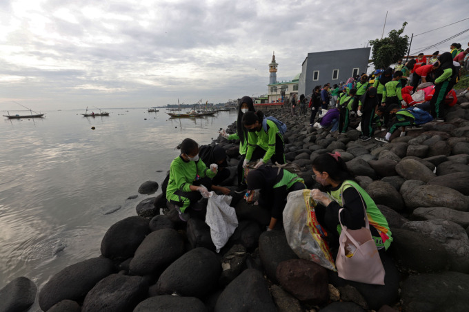GOTONG ROYONG: Sejumlah pelajar dan petugas bahu-membahu membersihkan sampah di kawasan Pantai Nambangan, Surabaya, Minggu (29/1). (SURYANTO/RADAR SURABAYA)