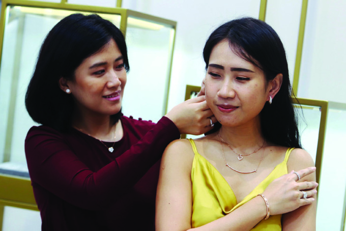TREN PERHIASAN: Silviana Tedjo (kiri) memasangkan perhiasan kepada Claudia Carolina, pada salah satu gerai perhiasan di Ciputra World Surabaya, Senin (13/2). (ANDY SATRIA/RADAR SURABAYA)