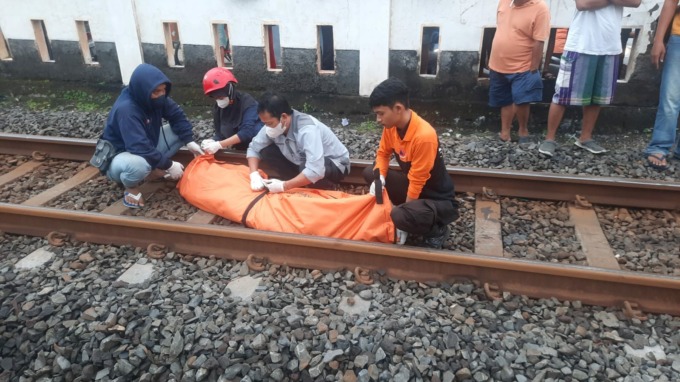 EVAKUASI: Petugas mengevakuazi jenazah Kusen yang terseret KA di Jalan Demak, Surabaya. (IST)