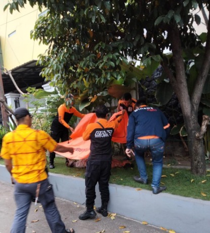 EVAKUASI: Petugas mengevakuasi jenazah Syahar di Jalan Kelantan, Surabaya.  (IST)