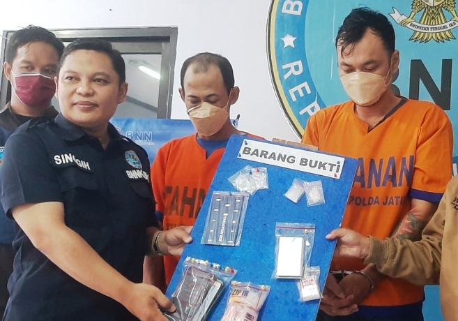 SATU JARINGAN: Kedua tersangka dan barang bukti diamankan di Kantor BNNK Surabaya. (MAHRUS/RADAR SURABAYA)