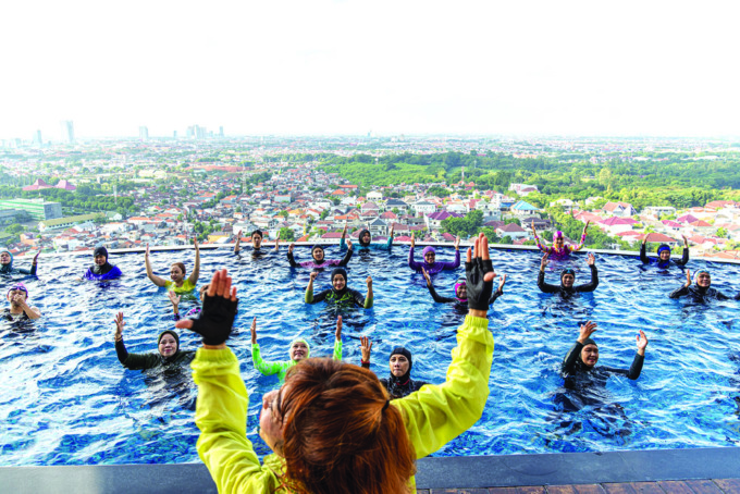 BONUS PEMANDANGAN KOTA: Kina Napitupulu memimpin aqua workout di kolam renang salah satu hotel di Surabaya Barat. (HILDAN SEPKA ADITYA/RADAR SURABAYA)