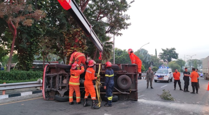 LAKA TUNGGAL: Petugas mengevakuasi truk boks yang terguling di Jalan Ahmad Yani, Surabaya, Jumat (14/4). (IST)