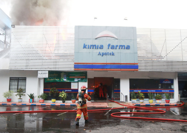 KEBAKARAN APOTEK: Petugas pemadam kebakaran Kota Surabaya berupaya memadamkan api yang membakar Apotek Kimia Farma di Jalan Diponegoro Surabaya, Rabu (5/4). (ANDY SATRIA/RADAR SURABAYA)