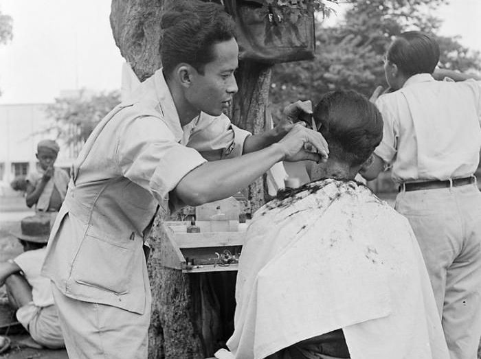 Keberadaan pangkas rambut di bawah pohon untuk melayani kaum pribumi. (ISTIMEWA/PINTEREST)