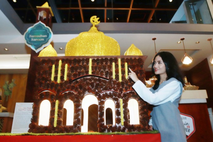 MINIATUR MASJID: Pengunjung mengamati miniatur masjid yang terbuat dari buah pinus kering yang dipajang di lobby Luminor Hotel Jemursari Surabaya. (ANDY SATRIA/RADAR SURABAYA)