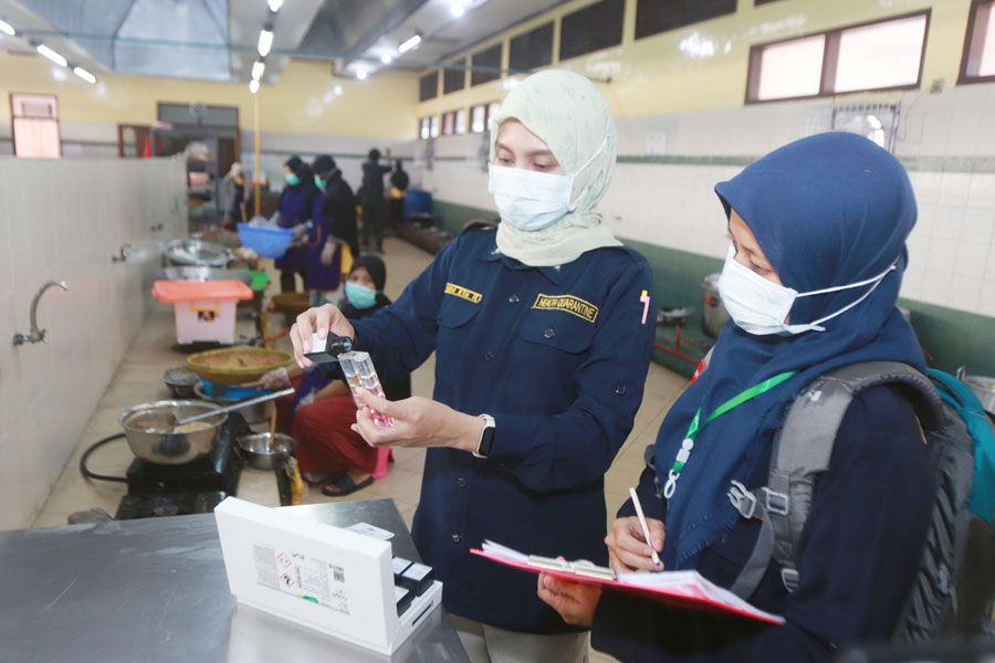CEK MAKANAN: Petugas Kantor Kesehatan Pelabuhan melakukan pengecekan makanan sebelum disajikan untuk calon jemaah haji di Asrama Haji Embarkasi Surabaya, Jumat (26/5). (ANDY SATRIA/RADAR SURABAYA)