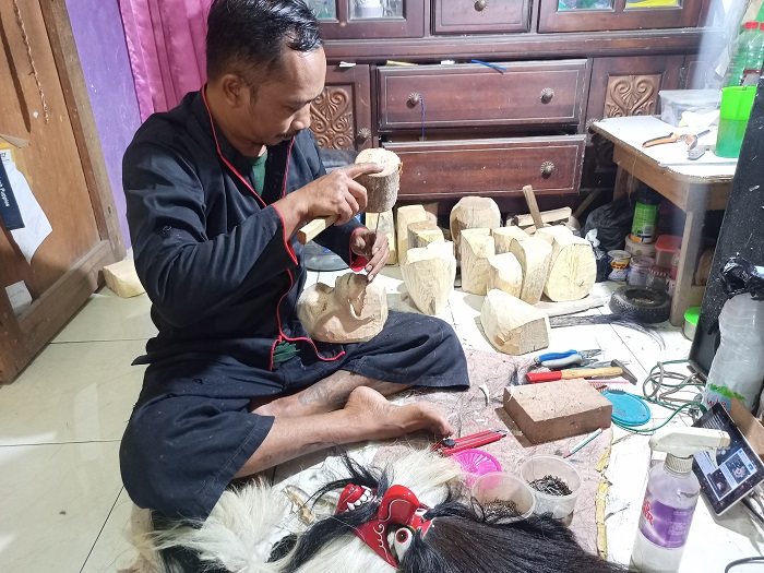 KREATIF: Maswanto memahat kerajinan krampus mask yang terbuat dari kayu cangkring.