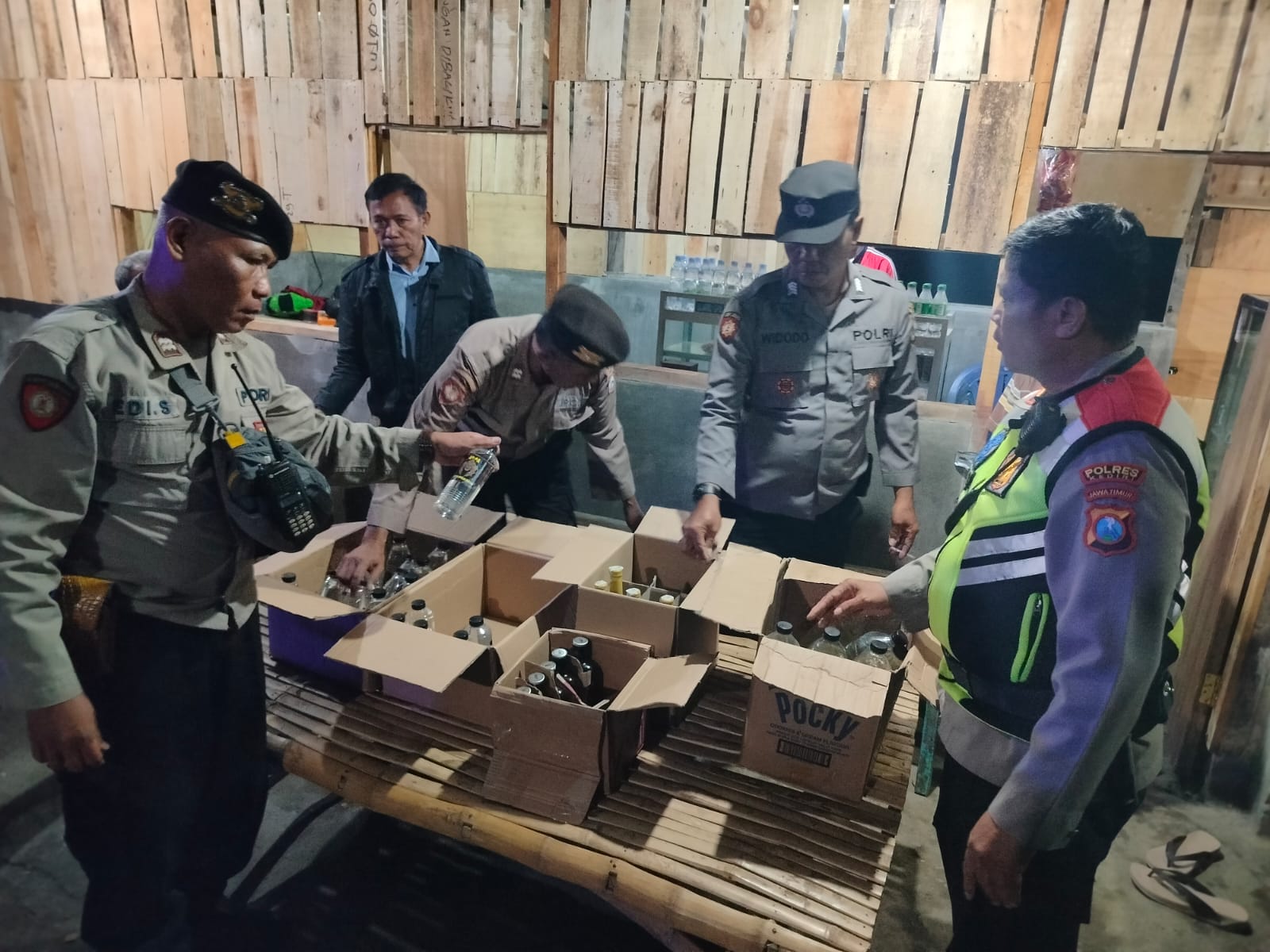 BISNIS GELAP: Petugas Polsek Mojoroto mengamankan puluhan botol miras ilegal yang disimpan dalam kardus di dapur warung, Kelurahan Lirboyo, Kecamatan Mojoroto.