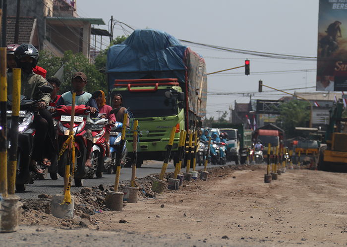 TERSENDAT: Pengendara kendaraan roda dua dan roda empat antre melintas di jalan depan Pasar Gringging yang kemarin dikerok separo.