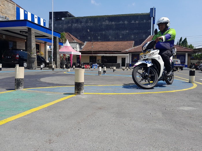 LEBIH MUDAH: Novan, anggota satlantas, memberi contoh mengendarai kendaraan melewati jalur berbentuk huruf S, di halaman kantor Satlantas Polres Kediri Kota.