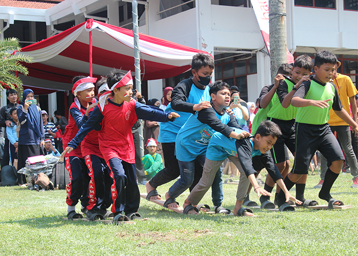 ADU CEPAT: Anak-anak berlomba lari terompah tandem dalam perayaan Agustusan.