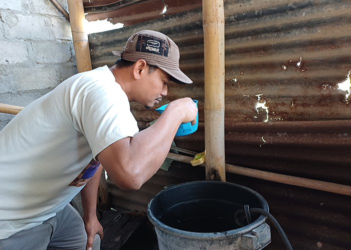 BERBAU: Salah satu warga Kelurahan Tempurejo, Pesantren mencium bau air sumur yang sepintas seperti solar.