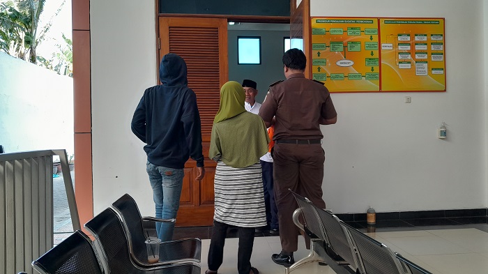 PESAKITAN: AS (peci hitam) bertemu keluarganya seusai menjalani persidangan di ruang Candra PN Kota Kediri kemarin siang.