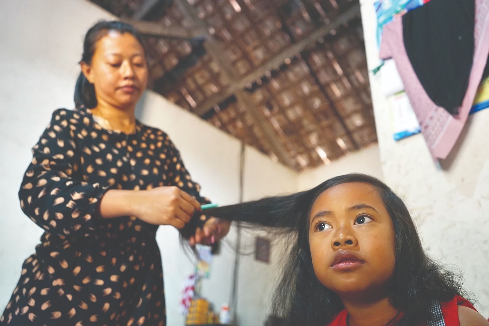 TRADISI RATUSAN TAHUN: Sunarti mengepang rambut gombak milik anaknya. Tradisi Gombak Kuncung akan hilang jika perempuan asal Desa Ngliman menikah dengan pria luar desa.
