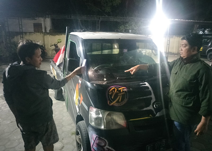 RETAK: Petugas menunjukkan kondisi kaca mobil yang menjadi korban pelemparan batu oleh ES dan MD kemarin.