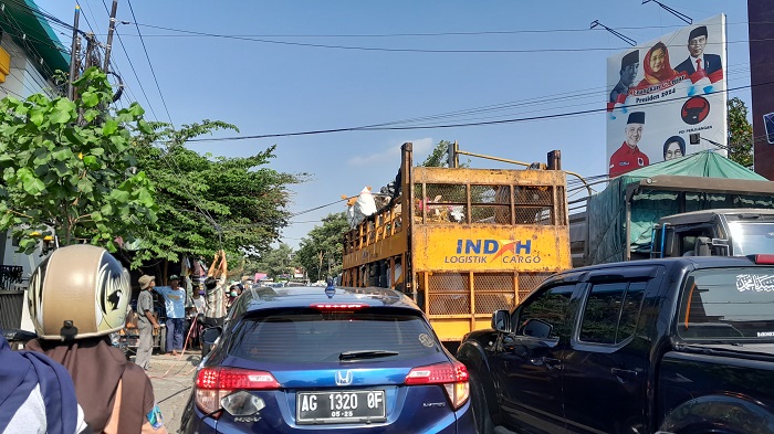 BIKIN REPOT: Warga terpaksa naik ke atas truk yang melintas agar kabel yang menjuntai tidak tersangkut kendaraan yang melintas di dekat Simpang Empat RS Baptis.