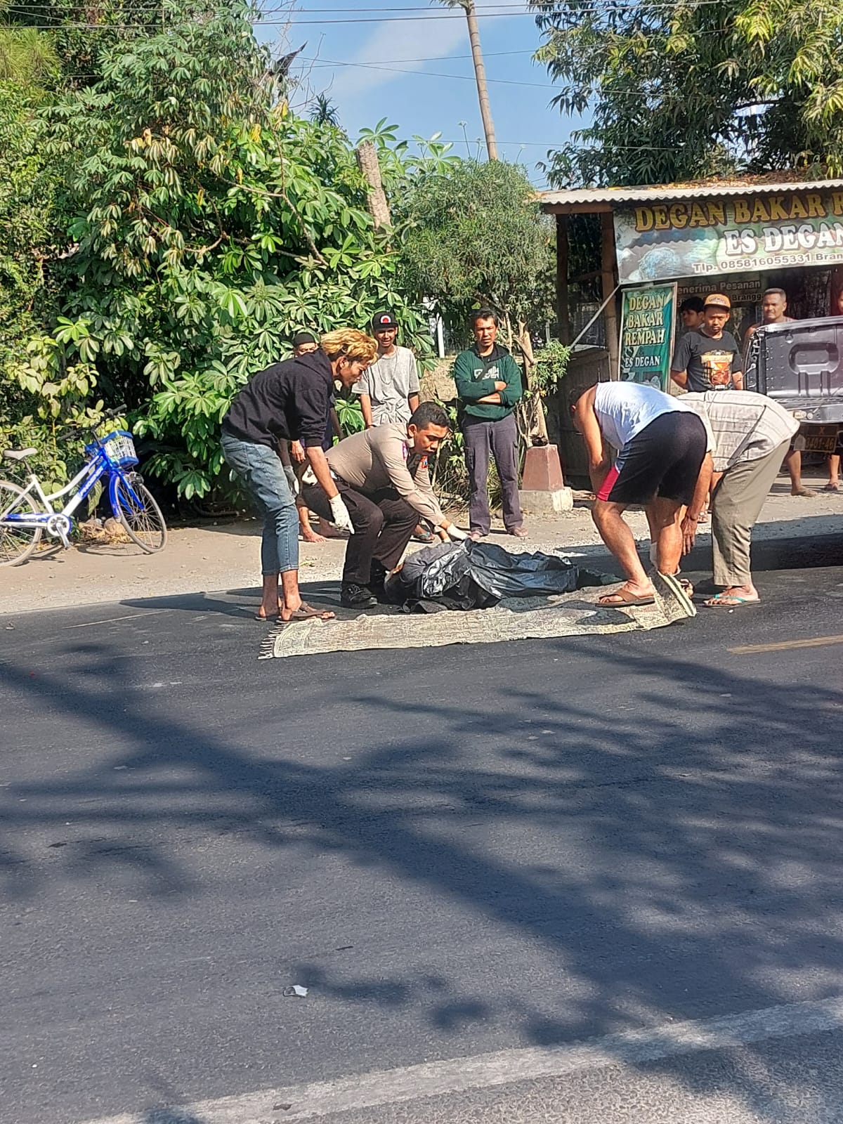 NAHAS: Petugas bersama warga mengevakuasi jasad Mardiono yang tewas di jalan raya Kediri Tulungagung, Desa Branggahan, Ngadiluwih.