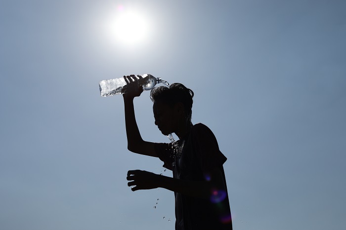 TERIK: Seorang bocah menyiramkan air mineral untuk mengurangi hawa yang panas. Kemarau terik tembus 35 derajat celsius.