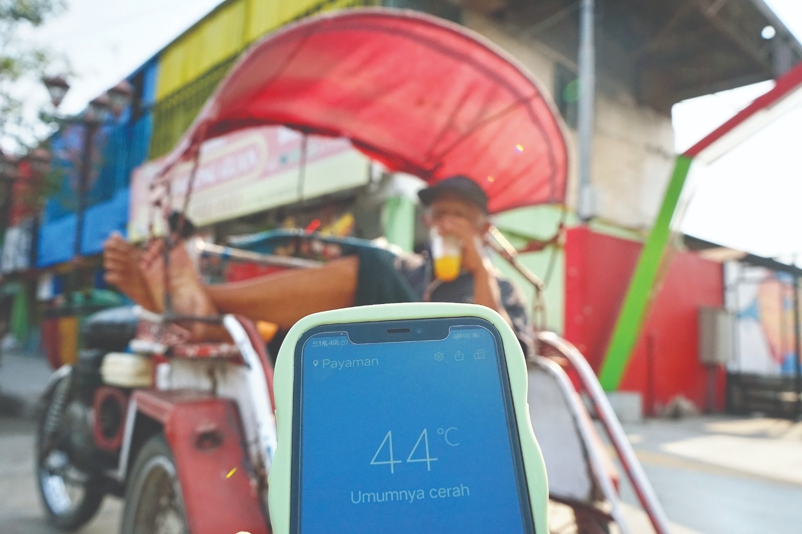 REKOR PANAS: Tukang becak meminum es jeruk saat mangkal di Kelurahan Payaman. Suhu di Kota Angin mencapai 44 derajat celcius kemarin.