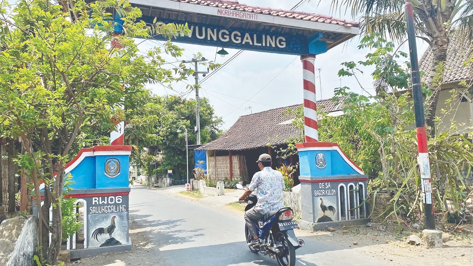 PEJABAT DILARANG MASUK: Pengendara motor melewati gapura Dusun Sawunggaling