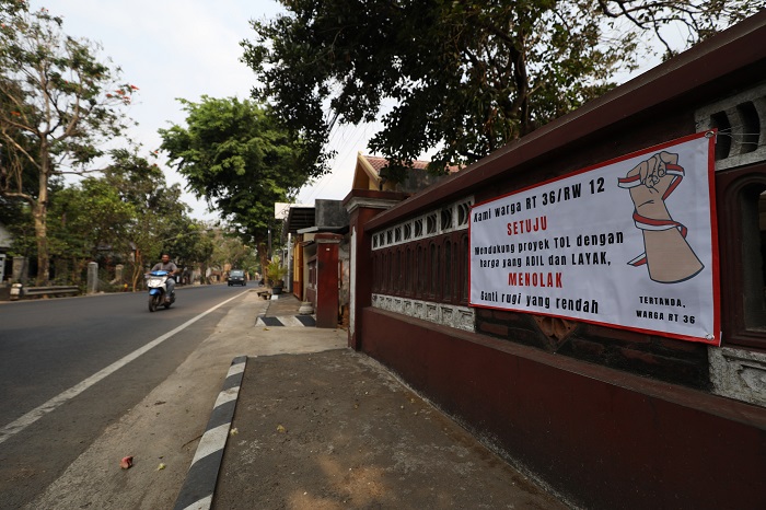 TERLALU MURAH: Warga Jl Suparjan Mangun Wijaya yang terdampak pembangunan Tol Kediri-Tulungagung memasang banner di rumahnya sebagai wujud protes hasil appraisal tanah yang dinilai terlalu rendah dari