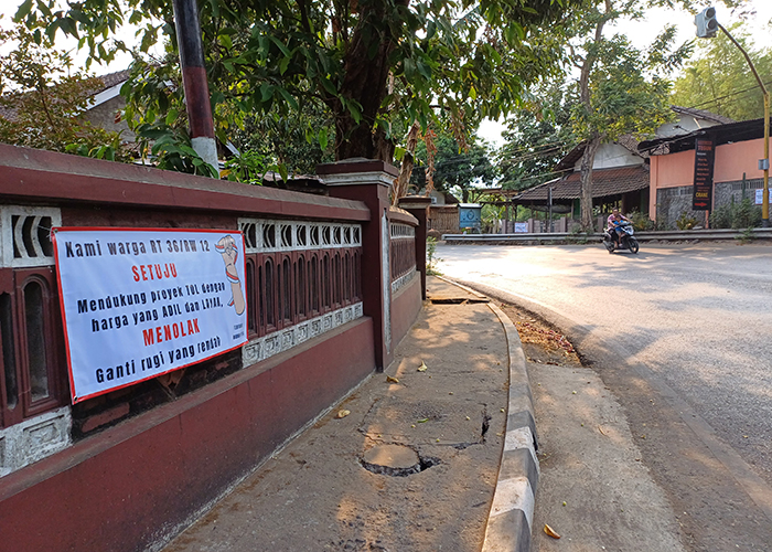 AKSI DAMAI: Sejumlah banner bernada protes tentang hasil penaksiran harga tanah terdampak Tol Kediri-Tulungagung di Jl Suparjan Mangun Wijaya masih terpasang di pagar rumah warga.