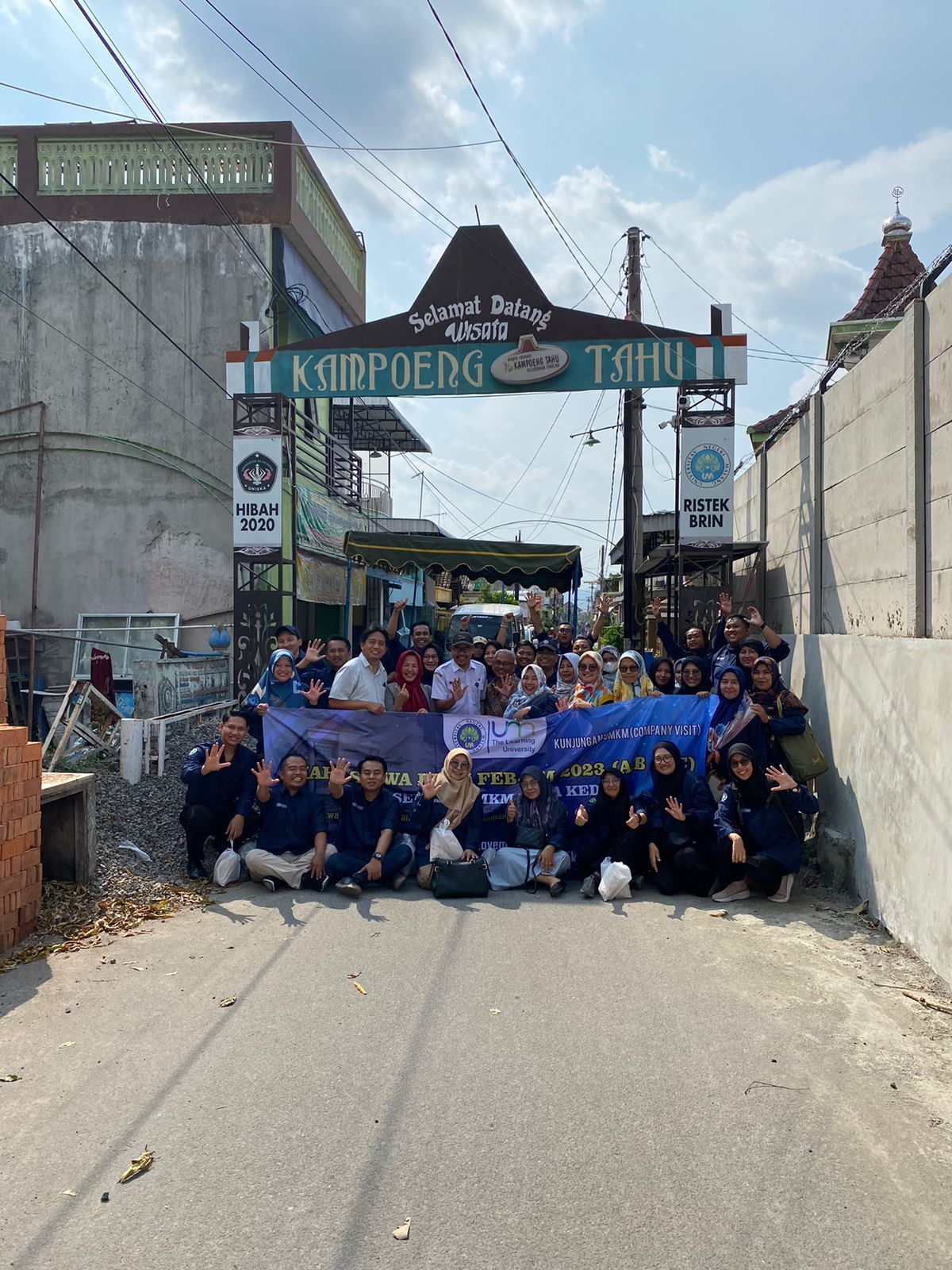 PEDULI: Mahasiswa dan dosen  pendamping PDIM UM foto bersama  pengrajin tahu CV. Wijaya Kembar di  depan pintu gerbang masuk Kampung  Tahu Kota Kediri.