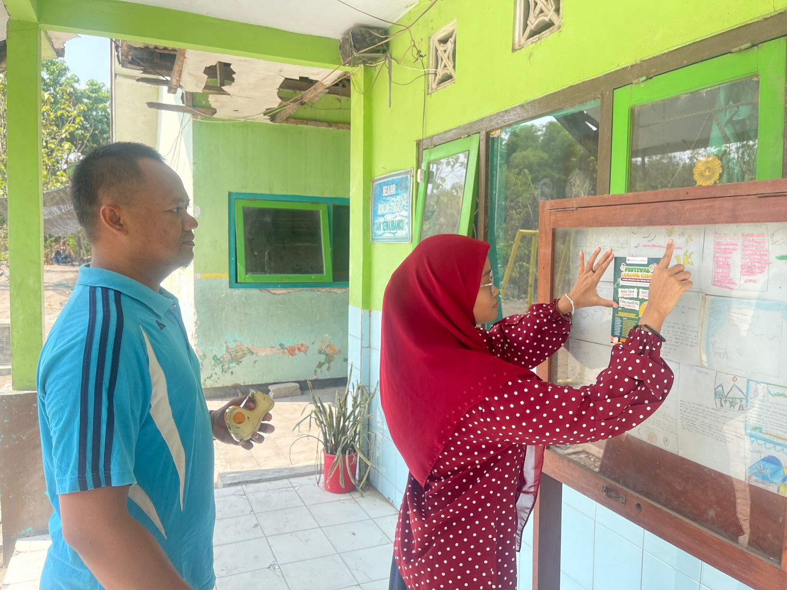 SIAP IKUT LOMBA: Guru MI Miftahul Ulum Desa Karangtengah, Kandangan menempelkan leaflet Festival Colour Kids di mading sekolah.