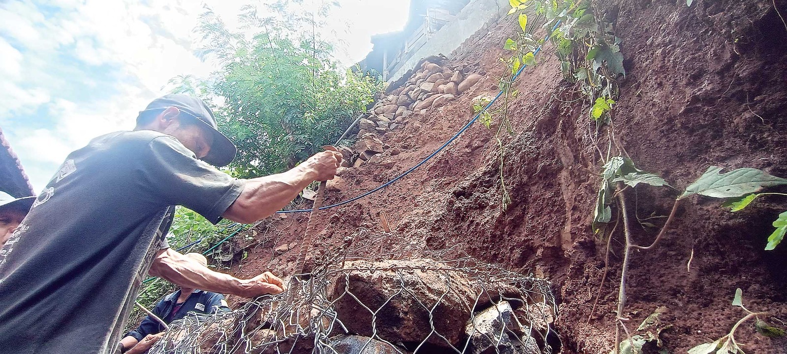 BERBAHAYA: Warga gotong royong memasang bronjong di tebing belakang rumah Panimin, Desa Kalipang, Grogol yang terkena longsor Kamis sore (4/1). (Foto: Asad MS/JPRK)