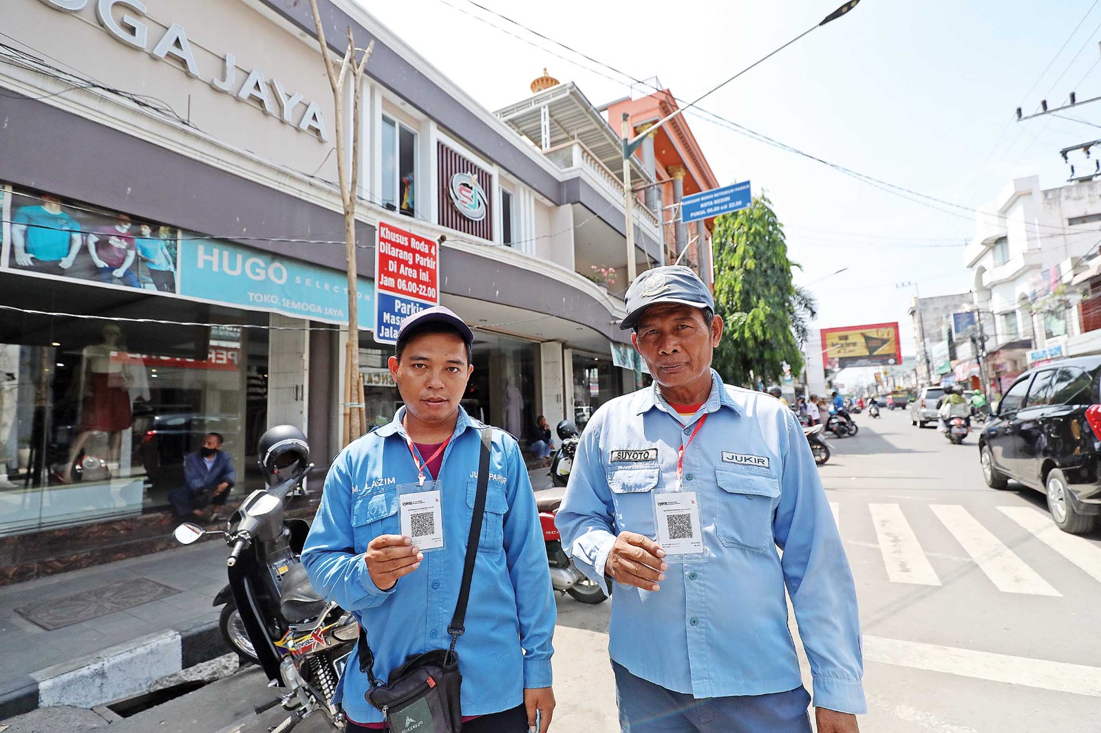 CEGAH PUNGLI: Jukir di Jalan Dhoho menunjukkan kartu QRIS.