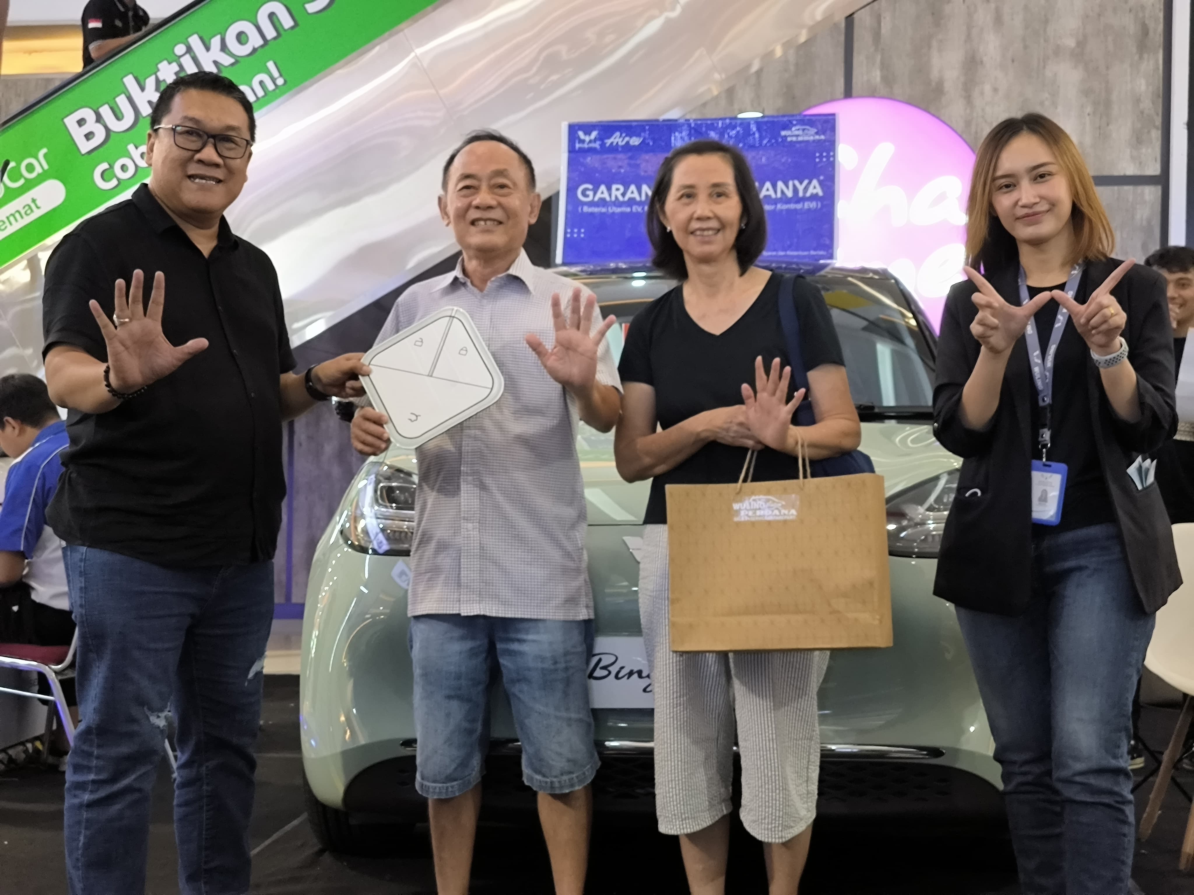 SIMBOLIS: BM Wuling Perdana Kediri Didik Purnomo (kiri) menyerahkan cenderamata berbentuk unit kunci kepada salah satu pembeli pertama Wuling Binguo EV, Sabtu (2/1). (Foto: Syaikhu Aliya Rahman/JPRK)