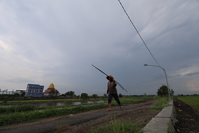MENDUNG GELAP:Seorang petani di Kelurahan Gayam,Kecamatan Mojoroto bergegas pulang karena langit sudah gelap. Ancaman hujan lebat disertai dengan angin kencang masih akan mengancam hingga pertengahan.