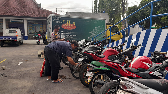 LAKUKAN PENGECEKAN: Petugas memeriksa sepeda motor dengan knalpot brong di halaman Satlantas Polres Kediri Kota. Tercatat, puluhan kendaraan roda dua diamankan menjelang Pemilu 2024.