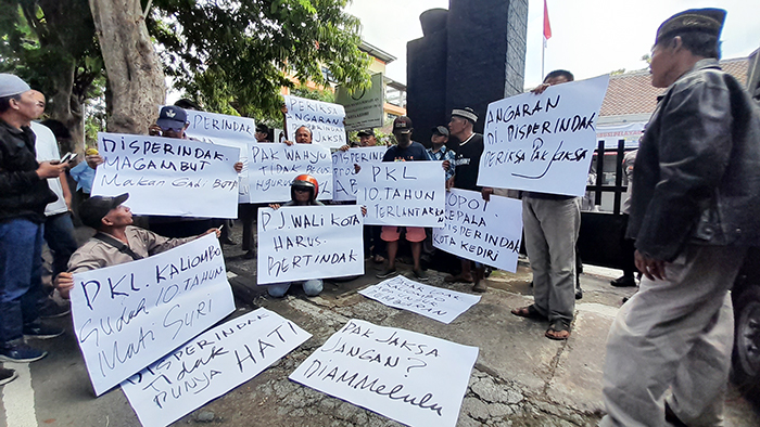 PROTES: Puluhan pedagang membentangkan poster dalam demo di kantor disperdagin kemarin. Mereka menagih janji pemkot terkait tindak lanjut relokasi 10 tahun silam.