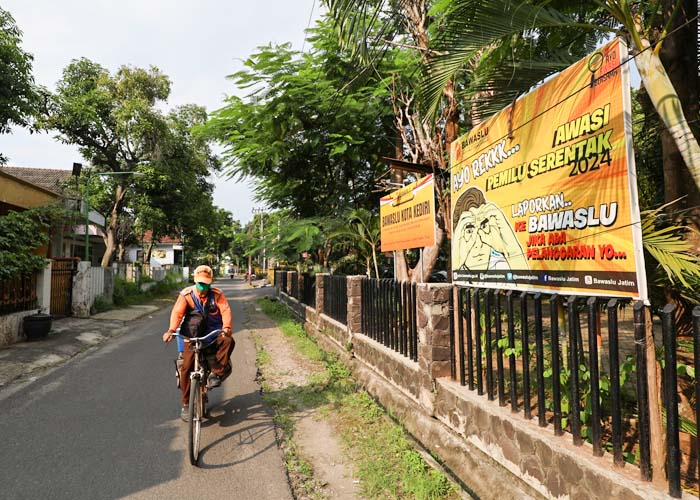SPANDUK PENGINGAT: Seorang warga melintas di dekat spanduk berisi imbauan pada masyarakat agar melapor bila mengetahui kecurangan dalam pemilu.
