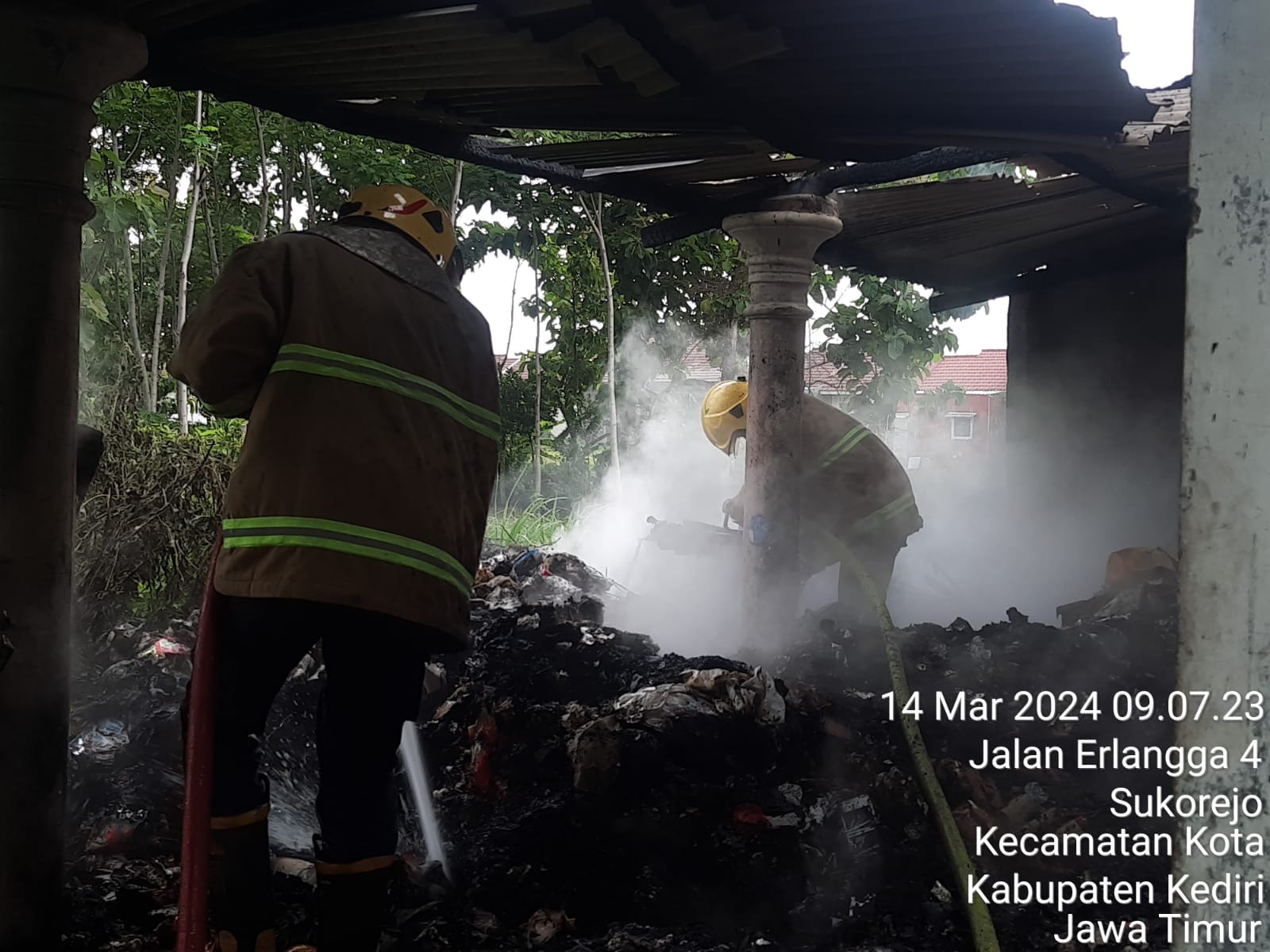 HANGUS: Petugas melakukan pembasahan gudang rongsokan yang ada di Desa Paron, Kecamatan Ngasem.