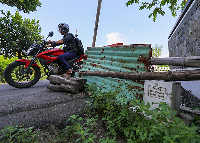RUSAK BERAT: Pengendara motor melintas di portal pembatas jembatan.