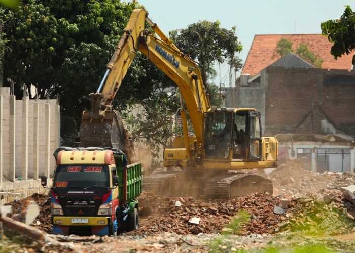 KEJAR DEADLINE: Satu unit backhoe meratakan bangunan di Jl Mayor Bismo yang terdampak pembangunan Tol Kediri-Tulungagung. Pembangunan tol senilai total Rp 9,9 triliun itu direncanakan  akhir Mei ini