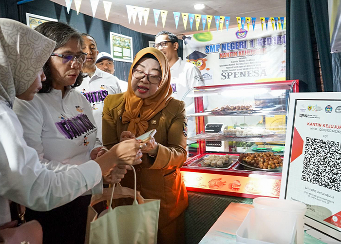 NONTUNAI: Pj Wali Kota Kediri Zanariah bersiap membayar jajanan yang dibeli di kantin kejujuran SMPN 1 Kota Kediri menggunakan QRIS.