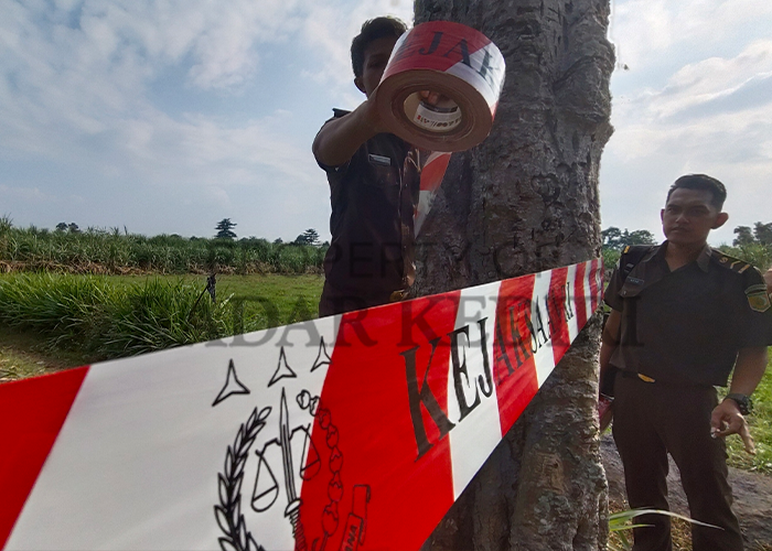 Tim Pidsus Kejari Kabupaten Kediri memasang garis larangan di areal lahan sitaan kasus korupsi di Desa Jambean, Kras.