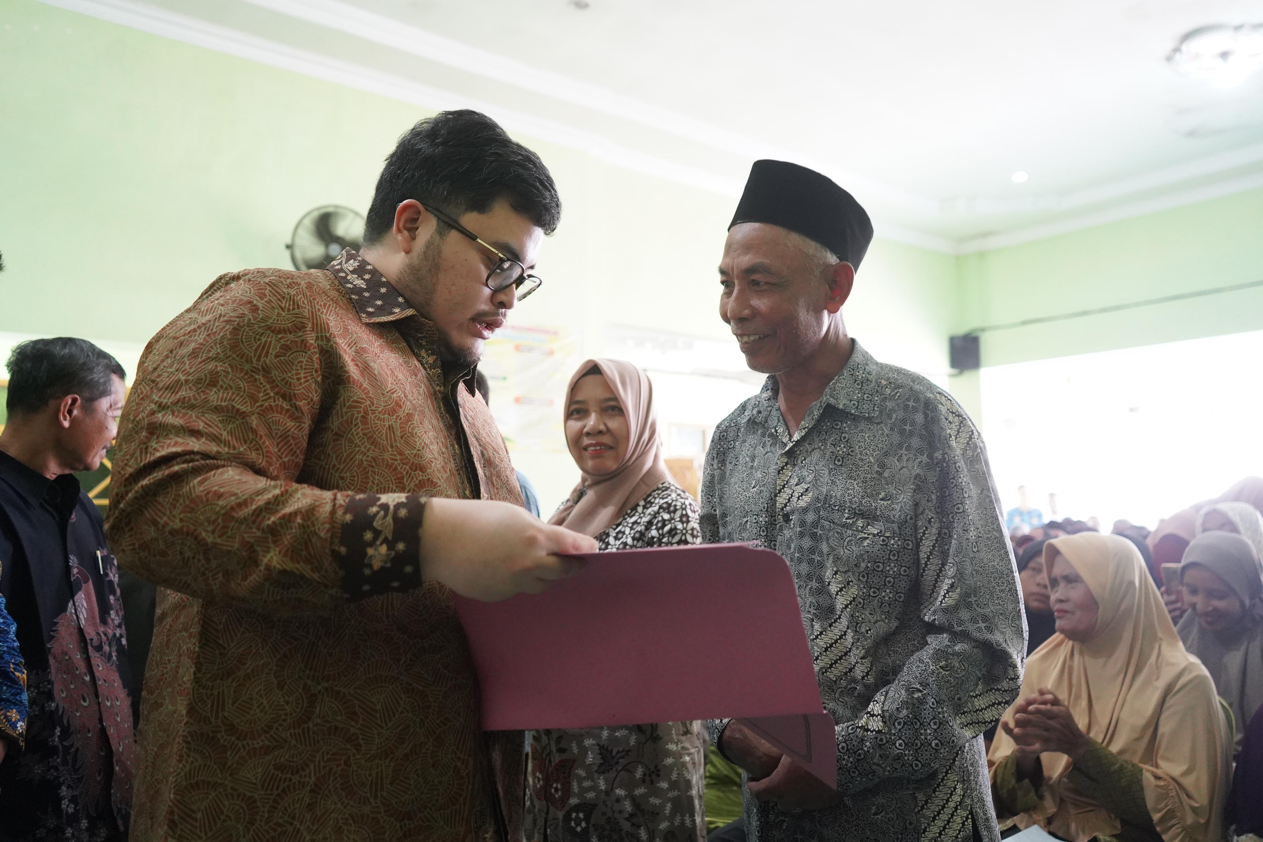 LINDUNGI ASET: Bupati Kediri Hanindhito Himawan Pramana (kiri) menyerahkan sertifikat tanah program PTSL kepada warga Desa Panjer, Plosoklaten.