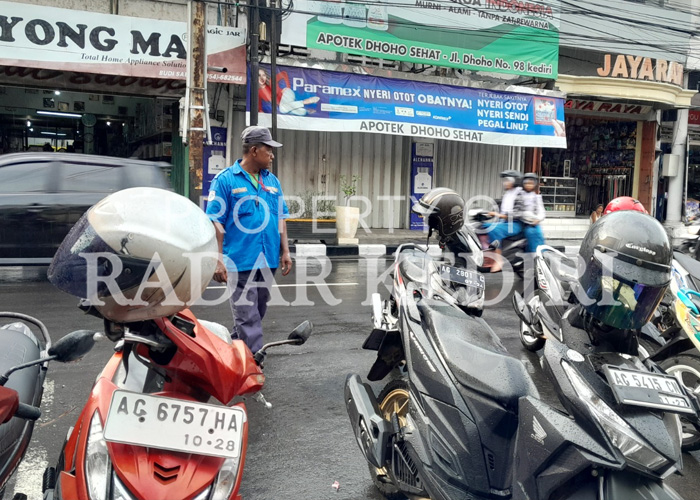 SUMBER PENDAPATAN: Juru parkir menata motor di kawasan Jl. Dhoho.