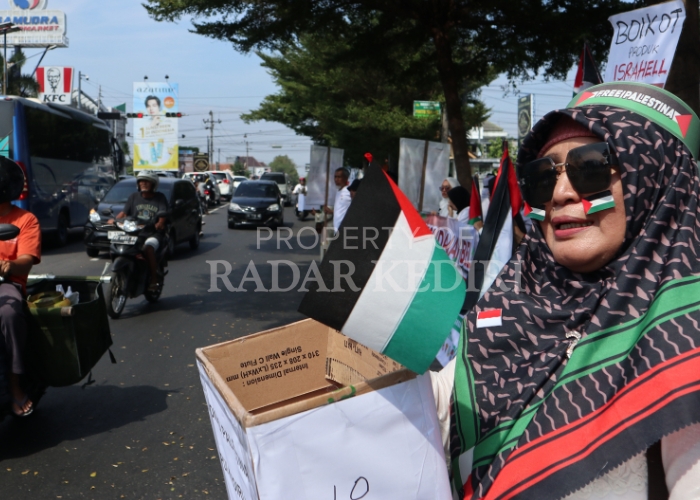 SOLIDARITAS: Seorang peserta aksi untuk Palestina memegang kotak donasi bagi pengendara yang melintas di depan Masjid Agung Kota Kediri kemarin.