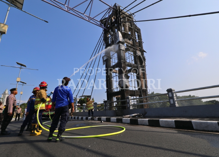 LAKUKAN PEMBASAHAN: Tim PMK Kota Kediri menyemprot pilar Jembatan Brawijaya untuk memastikan api yang melahap bagian bangunan proyek senilai puluhan miliar kemarin pagi sudah benar-benar padam.