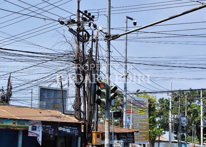 SEMRAWUT: Warga berjalan di bawah tumpukan kabel yang berada di perempatan Terminal Tamanan, Kelurahan Campurejo, Mojoroto. Keberadaan kabel merusak wajah Kota Kediri.