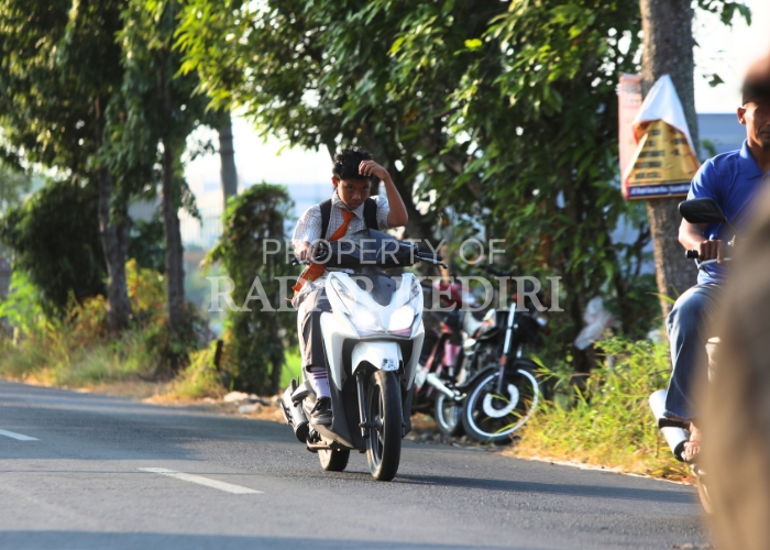 Pelajar di Kota Kediri yang belum mengantongi SIM nekat mengendarai sepeda motor ke sekolah tanpa memakai helm.