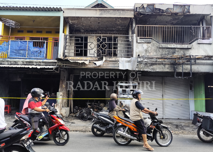 TRAUMA: Pengendara motor melewati tiga ruko yang terbakar pada Jumat (14/6) dini hari